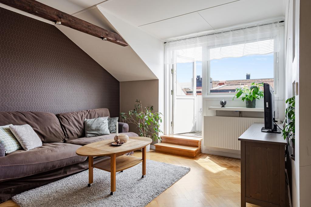 Vardagsrum med snedtak, brun fondvägg och plats för både soffgrupp och soffbord