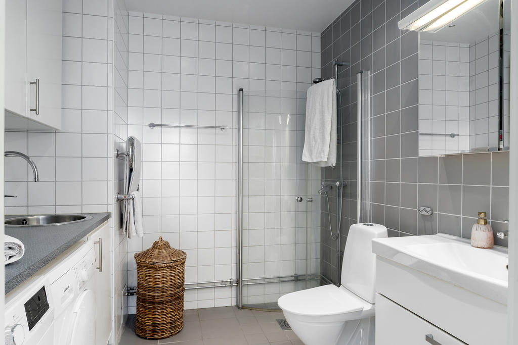Modernt badrum med generösa ytor, tvättmaskin, torktumlare och stilrena materialval.