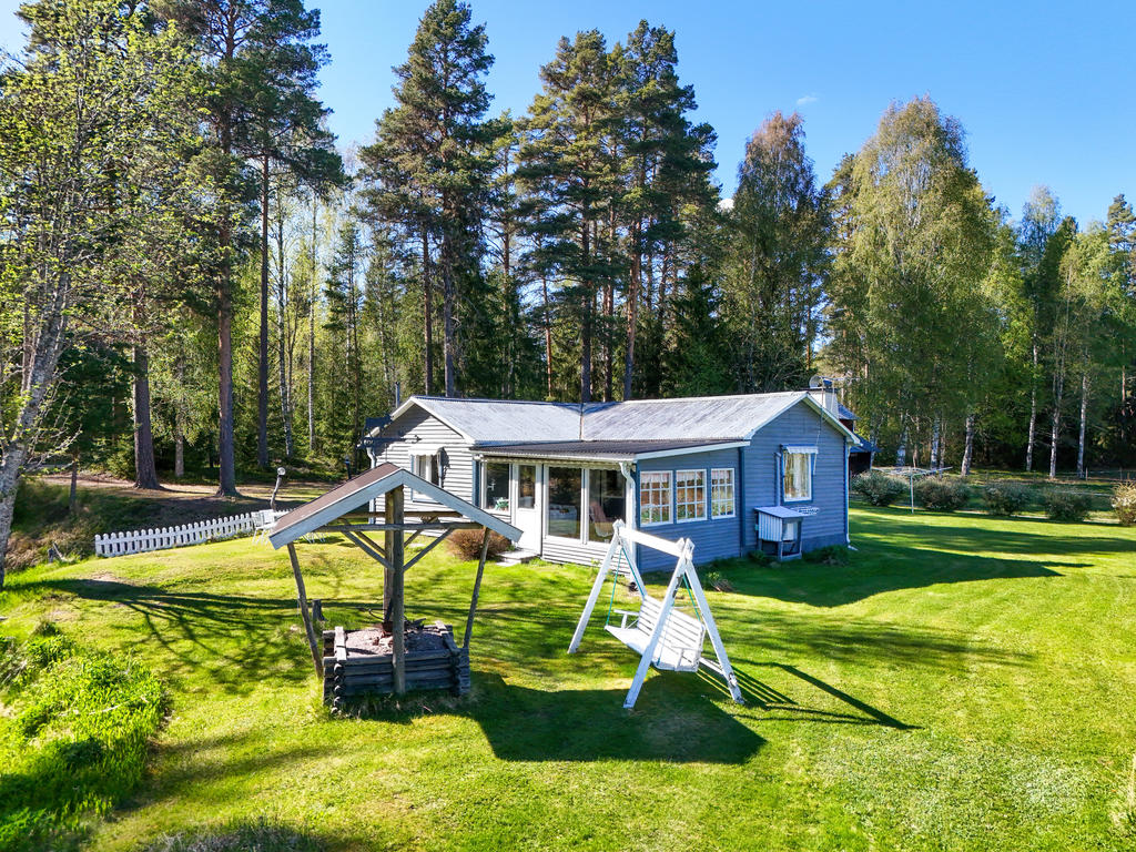Grillplats på tomten intill stugan och dess inglasade altan. 
