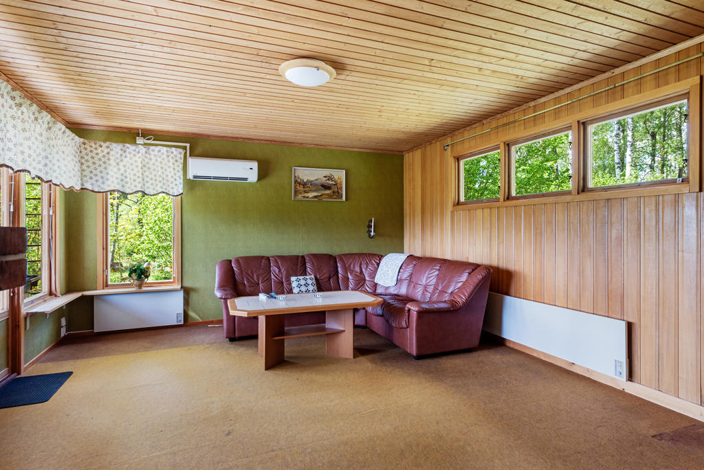 Vardagsrumsväggarna är beklädda med träpanel samt grönskiftande tapet. Enklare matta på golvet.