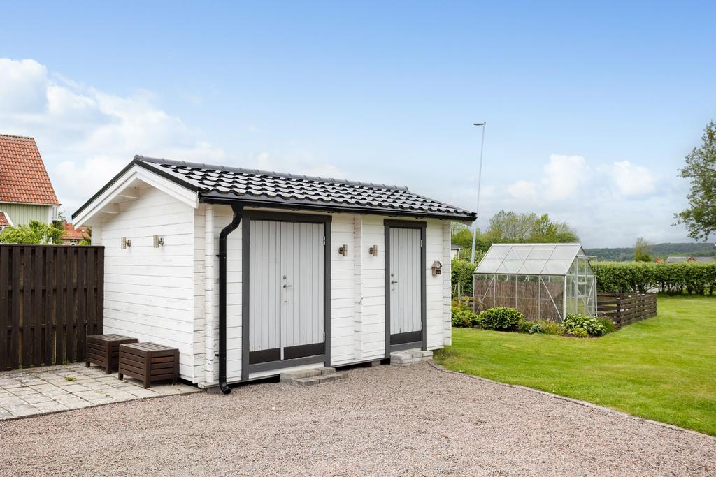 Den grusade infarten erbjuder gott om plats för flera bilar och leder fram till ett praktiskt förråd för trädgårdsredskap och odlingstillbehör.