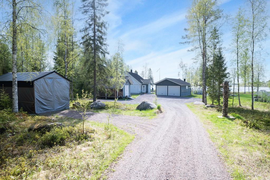 Infart. Praktsikt byggtält till vänster. Rejäl boda längre fram till vänster. Dubbelgarage samt huvudbyggnad.