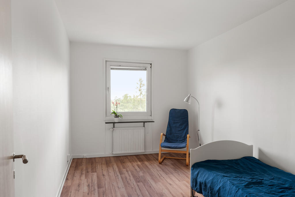 Stort sovrum med fönster mot den lummiga bakgården.