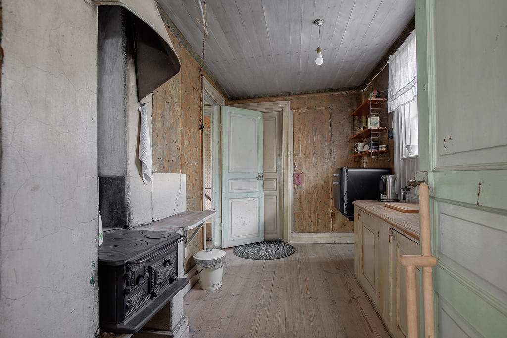 Köket i gårdshuset med kylskåp och gamal gjutjärnsspis