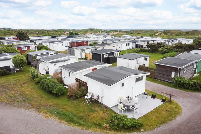 Välkommen till Knoten 109B! En välplanerad tomtyta med uteplats i anslutning till entrén, omgiven av gräsmatta och gångväg
