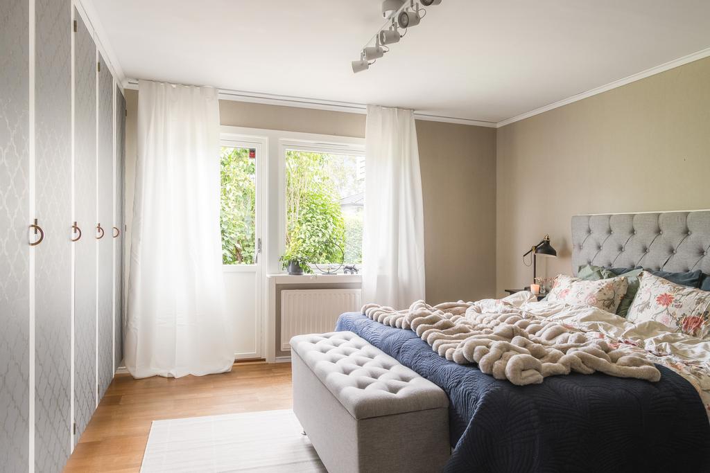 Det stora sovrummet på entréplan har ljusbruna väggar, gott om garderober samt en altandörr som leder ut till trädgården