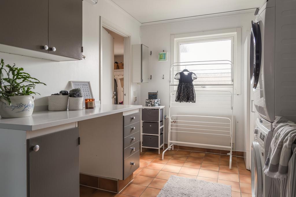 Tvättstuga med praktisk arbetsyta och gråa skåpsluckor. Här finns gott om förvaring och plats för både tvättmaskin och torktumlare. 