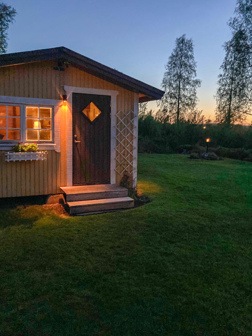 Kvällsbild på Stuga/förråd och trädgård (kundfoto)