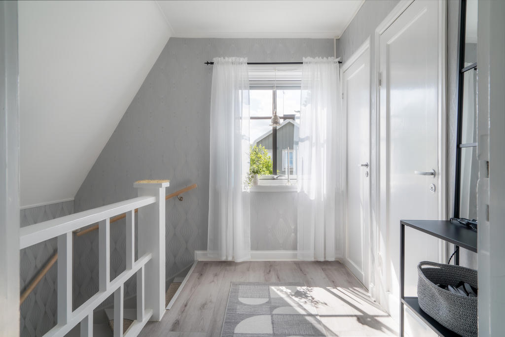 Hallen på övre plan med dörr till badrum samt dörr som leder till trappa upp till vinden