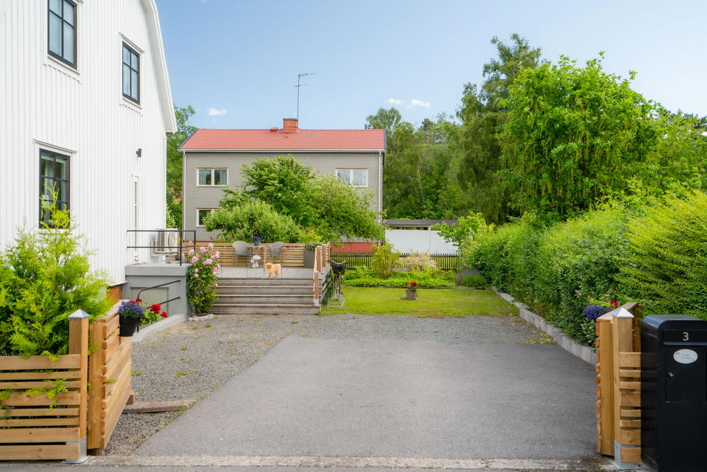 Häck, staket och uppfart med plats till två bilar. Källaringång på gavelsida.
