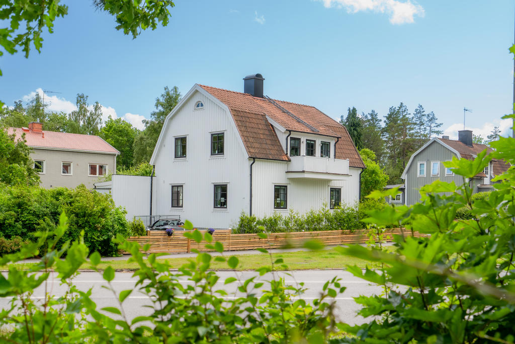 Vitt trähus med mansardtak, typiskt sekelskifteshus med karaktär.