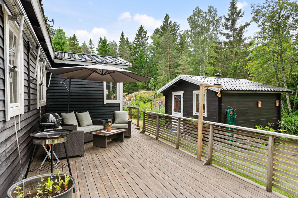 Stort trädäck längs med husets västsida samt ingången till gäststugan.