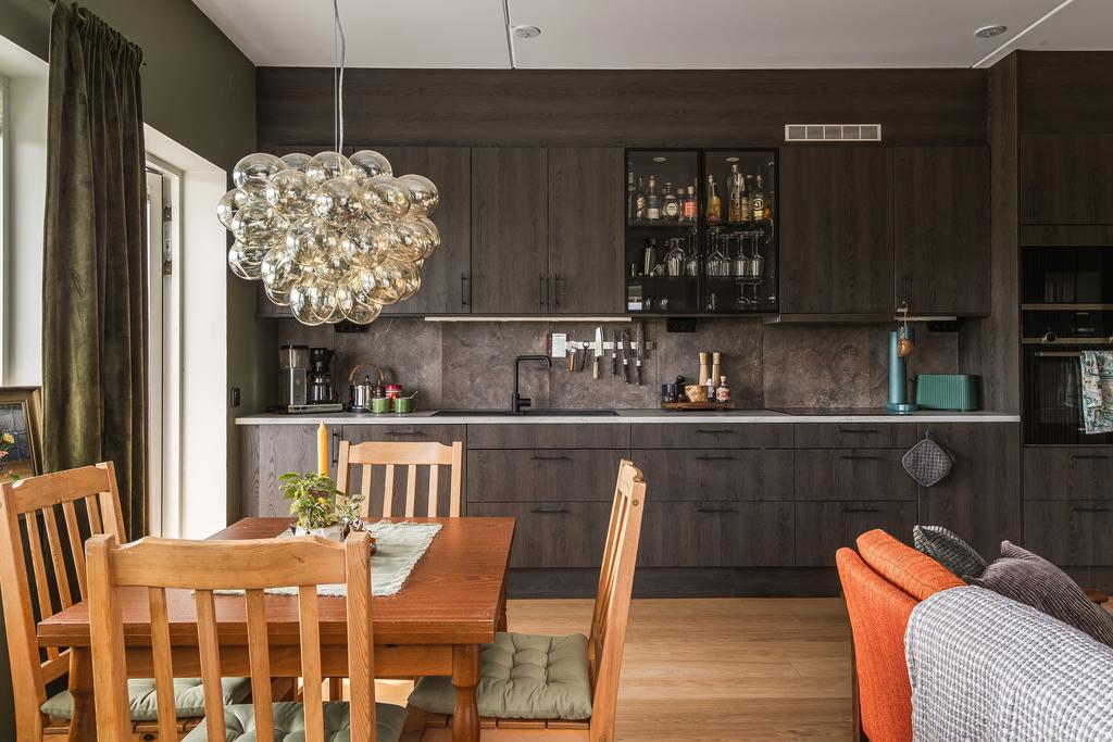 Köket är hemmets hjärta, med mörkbruna träskåp, svarta handtag och exklusiva 60x60-kakelplattor i gråbruna toner som ger en modern men samtidigt tidlös känsla.