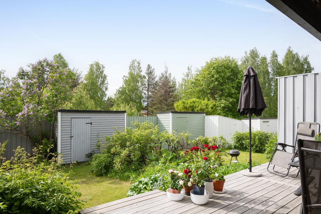 Mycket vacker baksida med altan, boda, planteringar, buskar och blommor