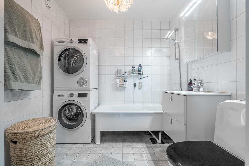 Smakfullt helkaklat renoverat badrum, utrustat med wc, handfat med kommod, badkar, tvättpelare och handdukstork.