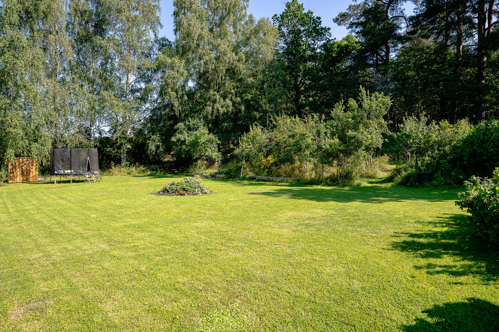 På husets nordvästra sida finns öppna gräsytor och en jordkällare i norra delen av trädgården