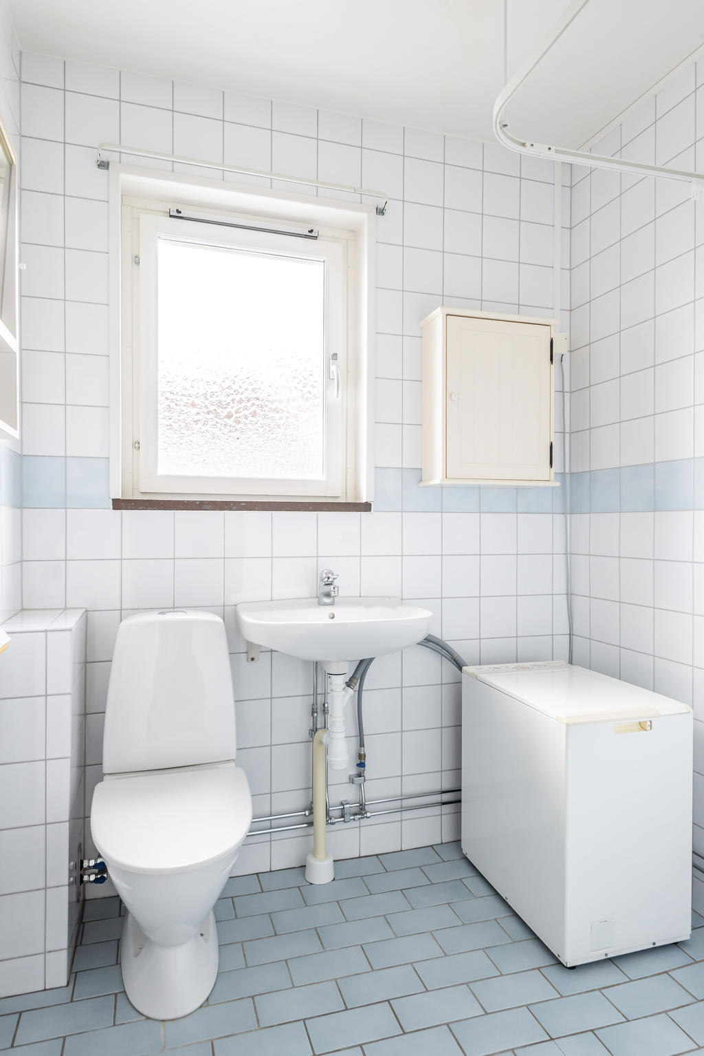 Kaklat badrum med dusch och tvättmaskin.