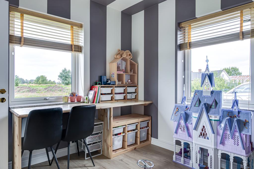 Barnrummet har ett skrivbordshörn vid fönstret och generösa lekytor i en genomtänkt barnvänlig miljö.