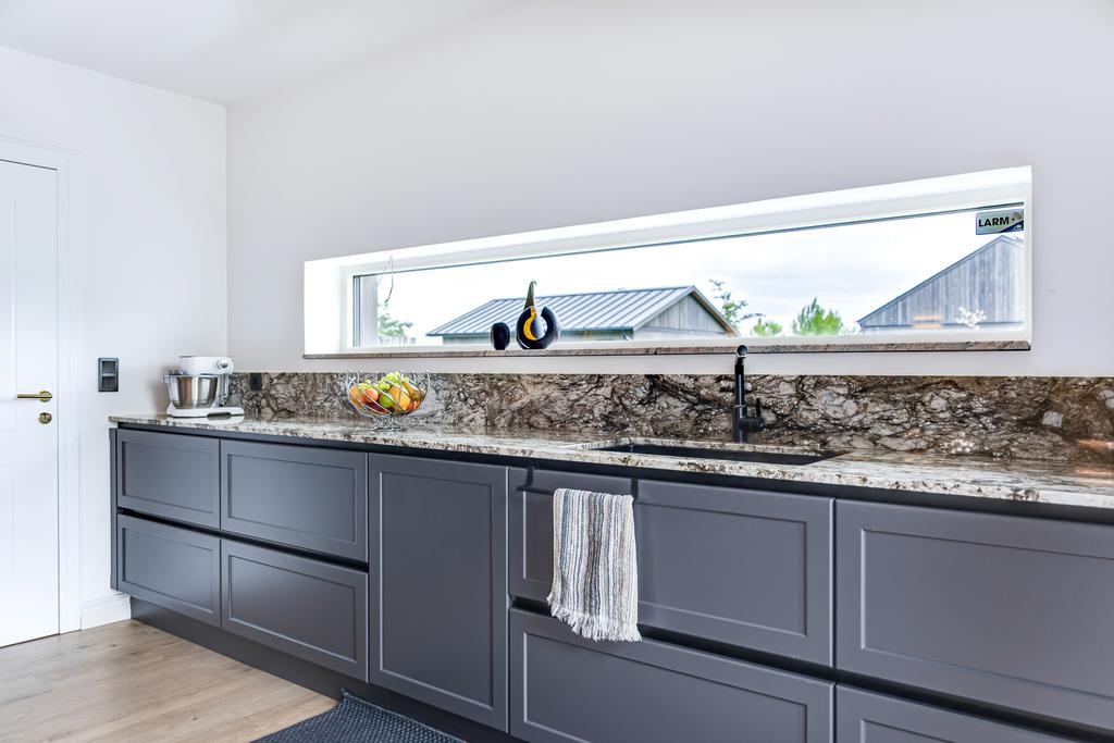 Lång granitbänkyta med utsikt mot trädgården – både praktiskt och vackert.