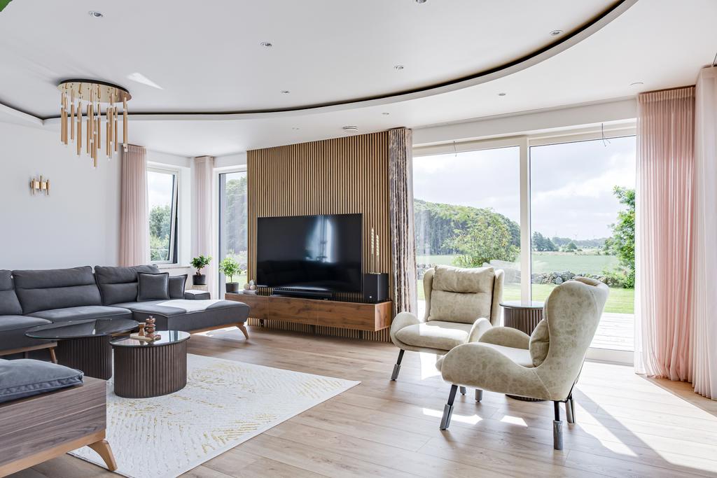 Elegant vardagsrum med stora fönsterpartier och panoramavy över natur.