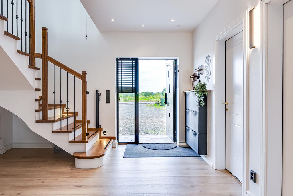 Ljus entré med påkostade materialval och öppen trappa i trä samt trappbelysning. 