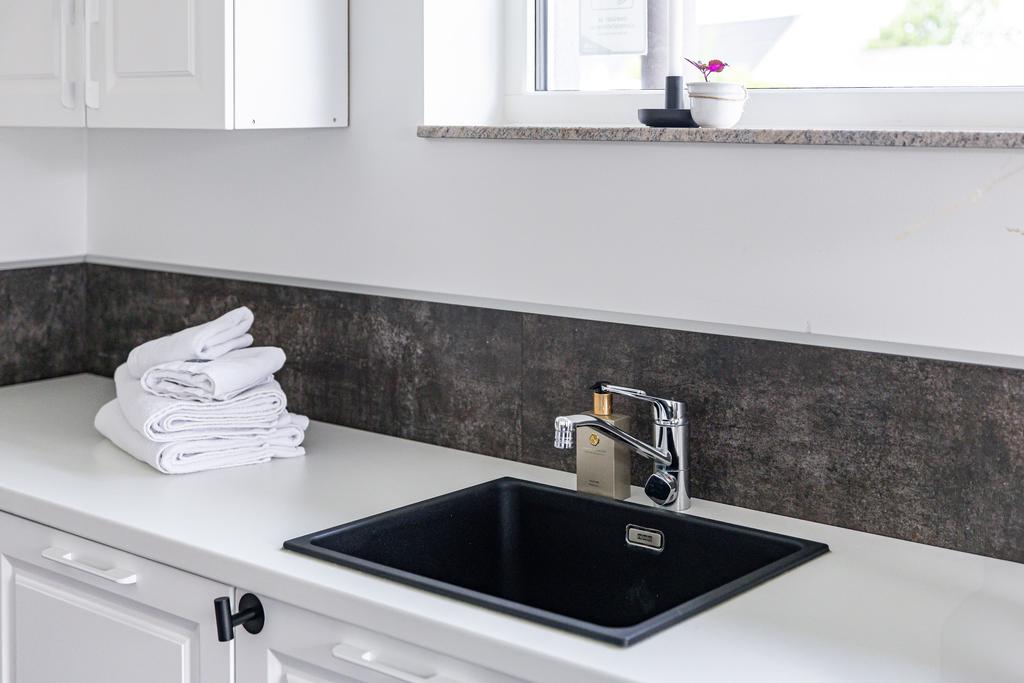 Tvättstugan är utrustad med ett stilrent handfat och stenskiva – både praktiskt och estetiskt tilltalande.