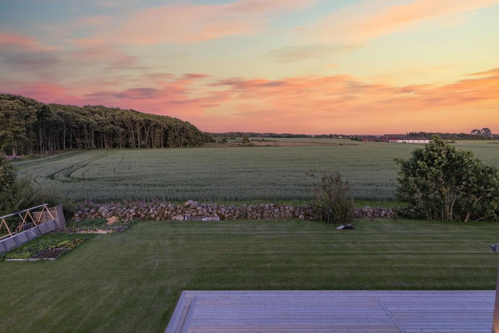 Den vackra baksidan ramas in av en låg naturstensmur som förstärker tomtens karaktär och markerar gräns mot omgivande landskap.