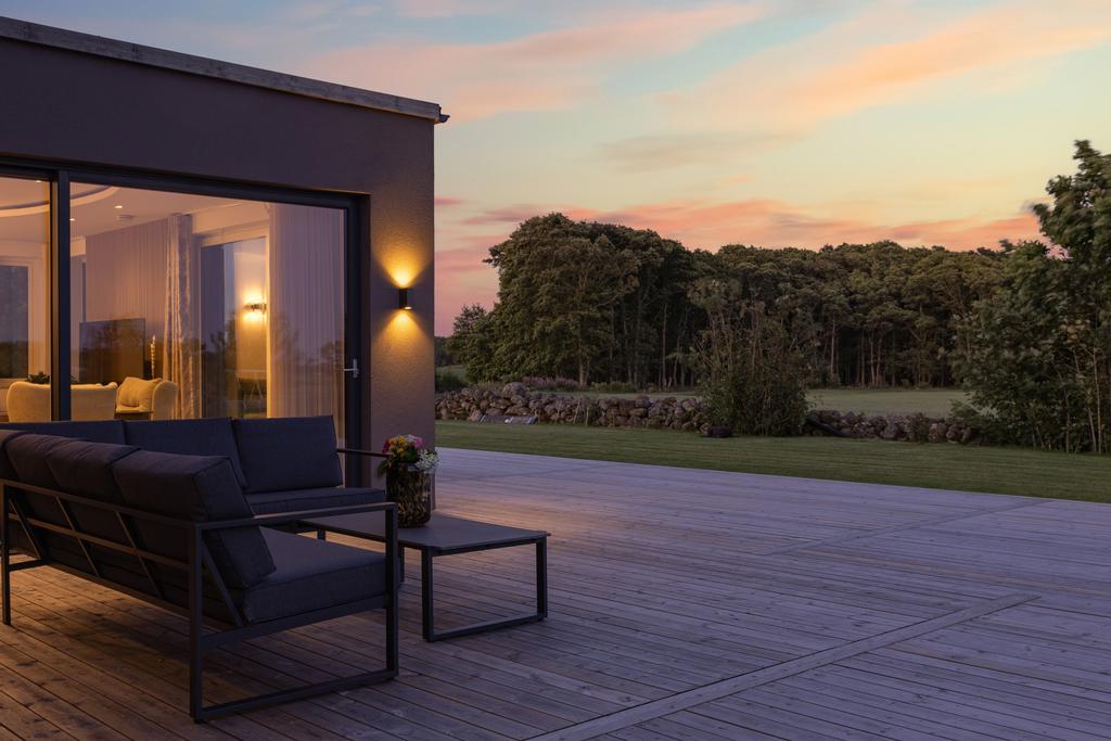 Kvällsbild på den loungehörnan med vy över trädgård och omkringliggande grönområde.