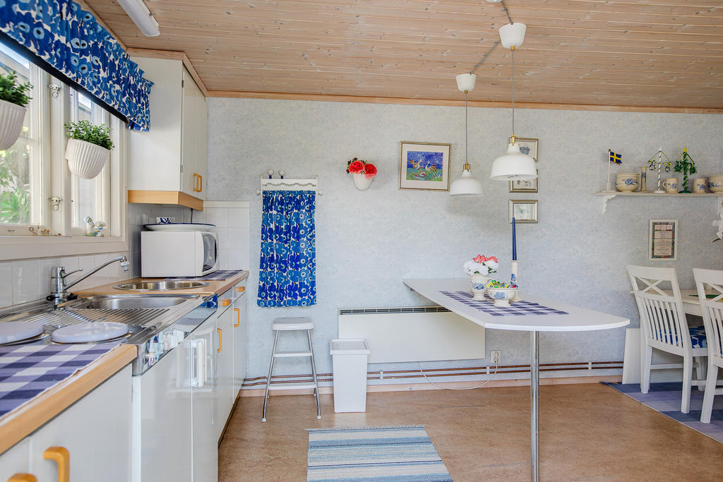 Kök med microvågsugn, spis och vask. Ugn i förrådsbyggnad