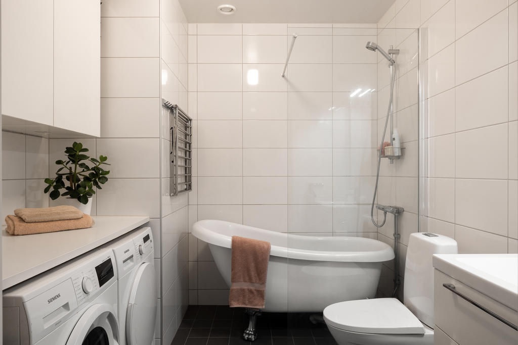Badrum med wc, kommod, dusch/badkar, tvättmaskin och torktumlare.