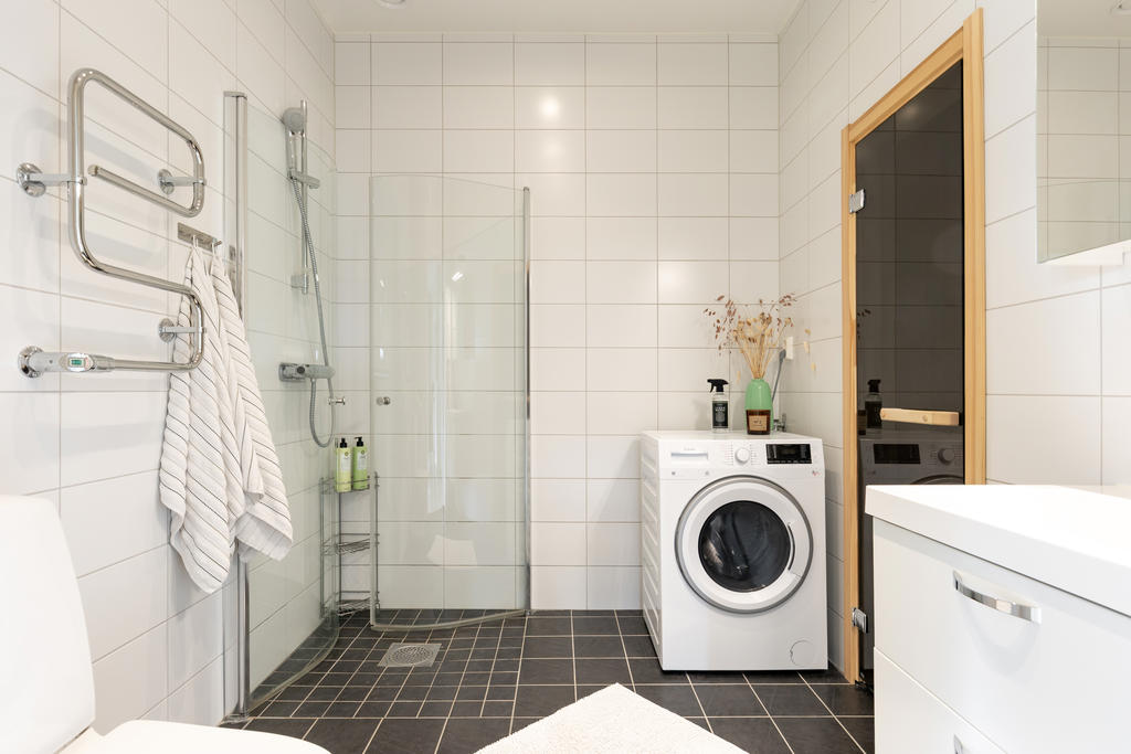 Generöst badrum med tvättmaskin, bastu och fina materialval.