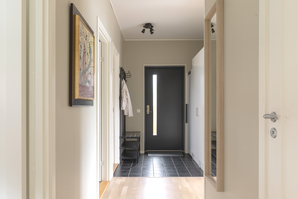 Hall med klinker på golv, garderober för förvaring och torkskåp.