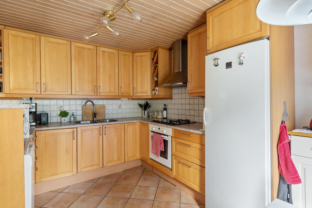I anslutning till vardagsrummet finns köket med bardel, luckor i ek delvis med vitrin,  arbetsbänk i laminat, stänkskydd i kakel, klinker på golvet med värmeslingor, panel i taket, fönster mot altanen.