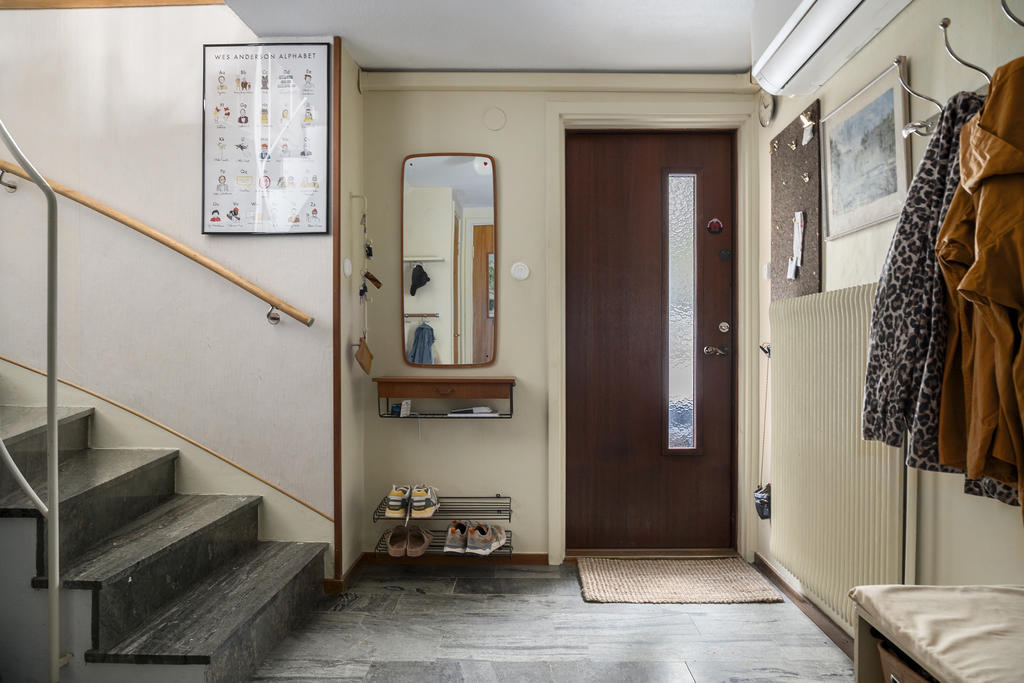 Rymlig hall där man genast ser den bevarade, praktiska charmen med stengolv