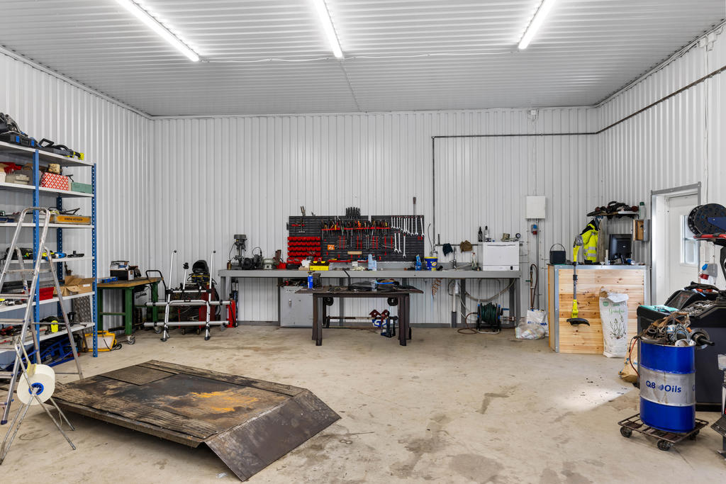 Verkstad/garage. Plåtbeklädda väggar, gjuten platta med golvvärme och 3,7 m i takhöjd.