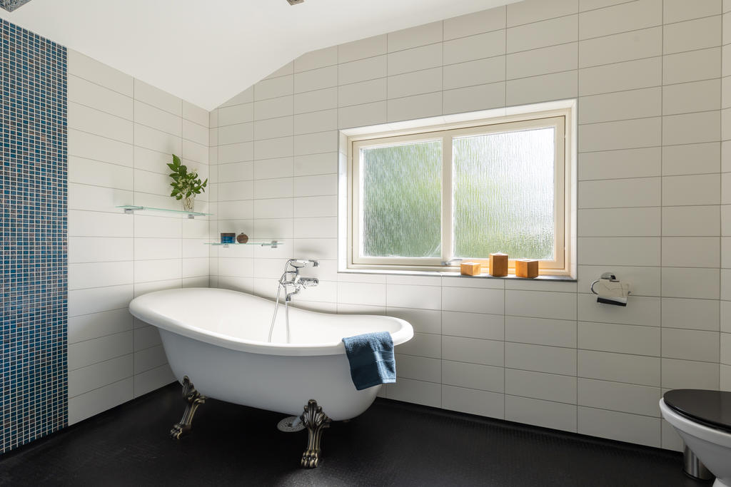 Stort badrum med badkar, dusch, wc och kommod