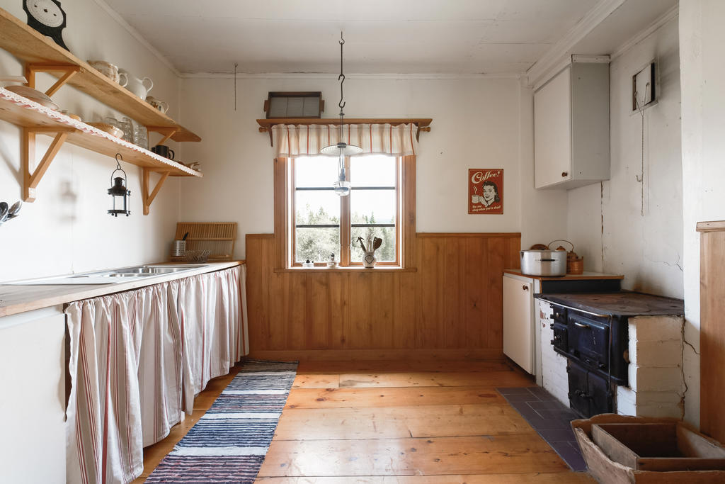 Ett väl tilltaget kök med plats för matbord. Här har du även en bänkskiva med stora arbetsytor, diskho och vedspis.