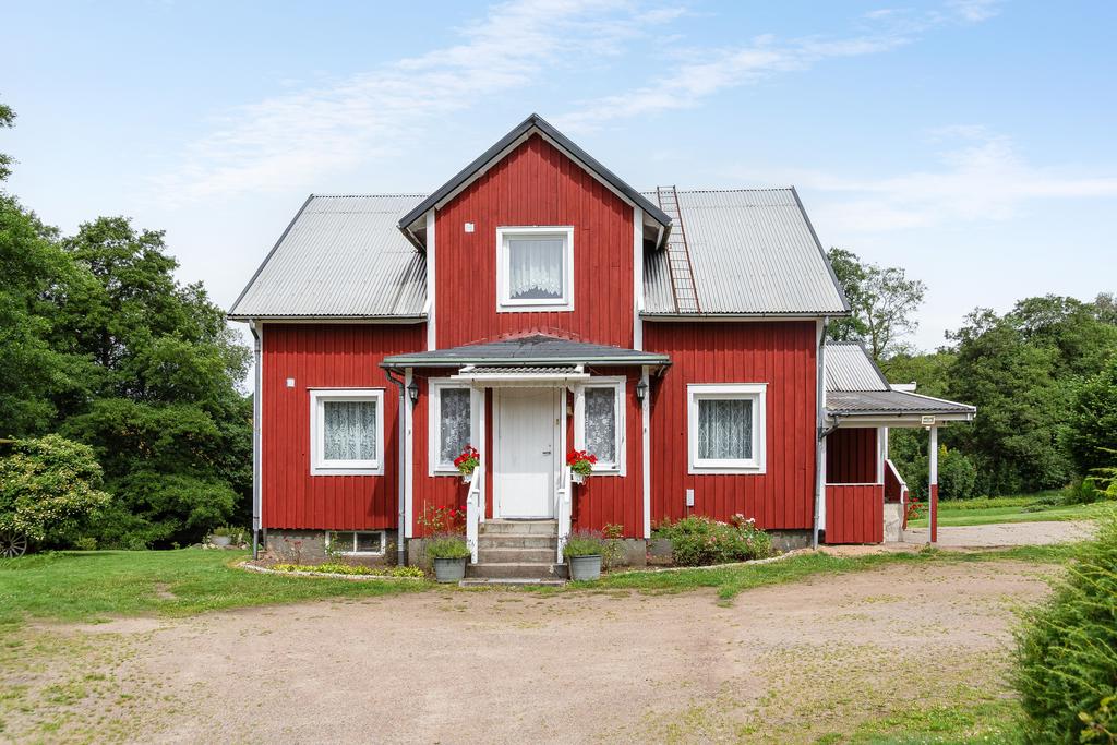 Välkomnande framsida med bred grusinfart och prydlig entré som ger en härlig gårdskänsla.