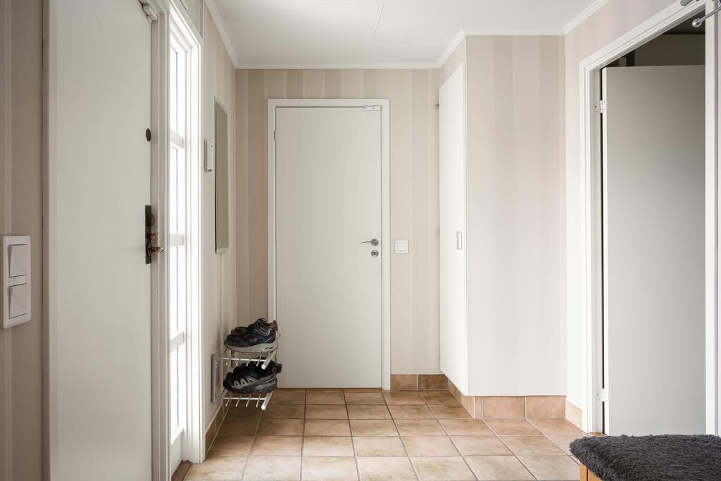 En smart groventré med klinkergolv och ljusa väggar, direkt i anslutning till både garage och tvättstuga. 