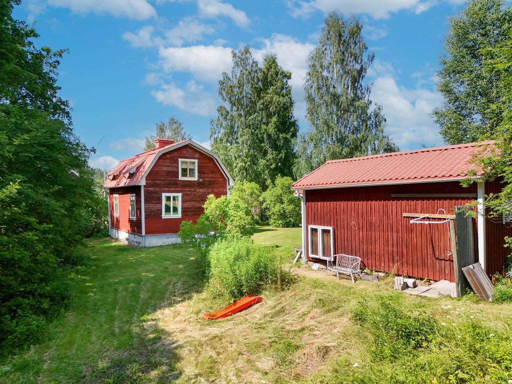 Vy från tomtens östra sida med en enkel utedusch bakom förrådsbyggnad. 