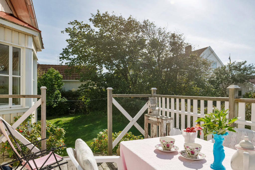 Uteplats på baksidan huset med trappa ner till den vackra lummiga gröna trägården.