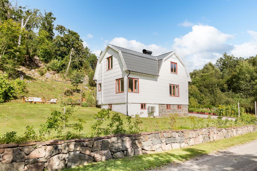 Vyn från grusvägen och mot huset, fin stenmur och häck som ramar in 