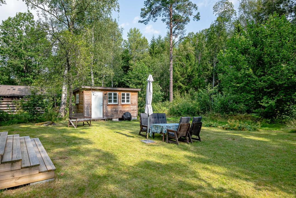 Mysig baksida med uteplats i gräset och gästhus