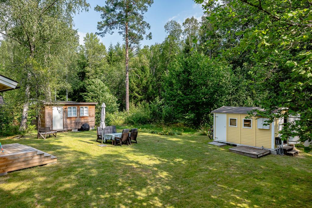 Baksidan med gästhus, uteplats i trädgården och trädgårdsförråd