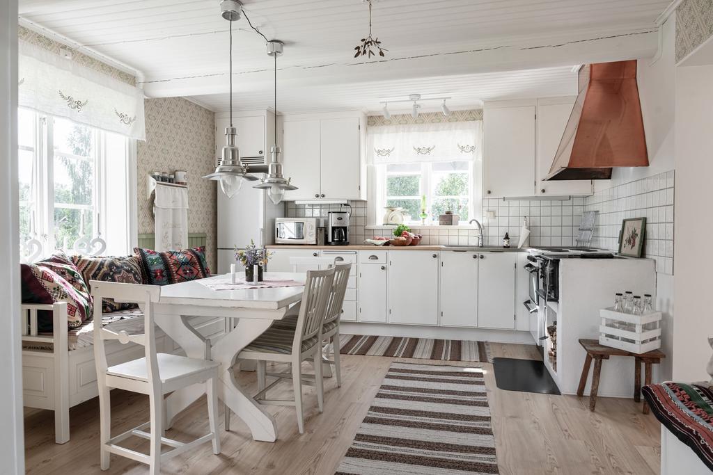 Ljust och hemtrevligt kök med klassiska detaljer, vedspis och plats för många kring matbordet.