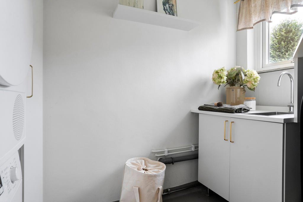I från köket nås en separat tvättstuga. Mycket ljus och trevlig. Smart planerad med plats för gästsängsförvaring. VA till pentry i lilla lägenheten ansluter här.