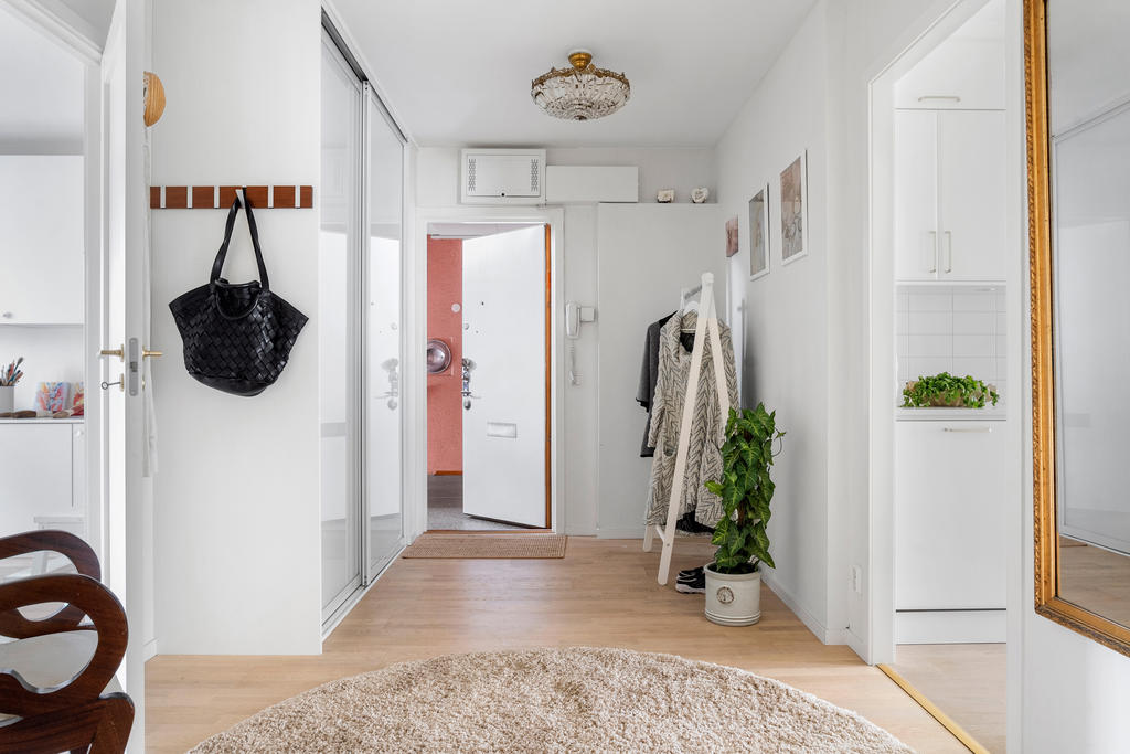 Rymlig hall med förvaring bakom skjutdörrar. Till höger om entrédörren finns dolt bakom vägg (tilläggsisolerat för ljud) dörr till lilla lägenheten.