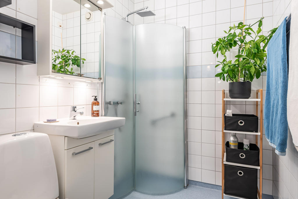 Snyggt badrum med duschhörna, tvättställskommod och wc. Kaklat och plastmatta.
