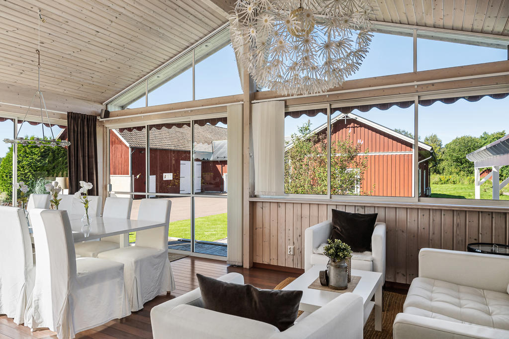 Inglasad altan med plats för matbord samt loungegrupp. 
