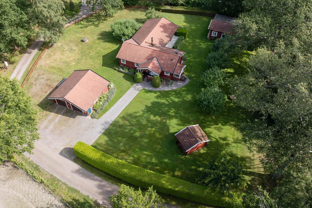 Översiktsbild över fastighetens bostadsbyggnad, garage, gäststuga och förrådsbyggnad.